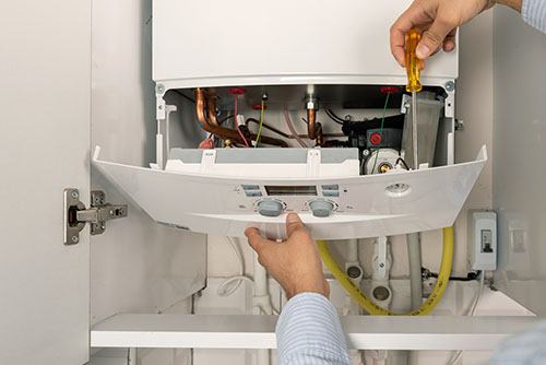 Heating technician repairing a residential boiler in Fountain Valley