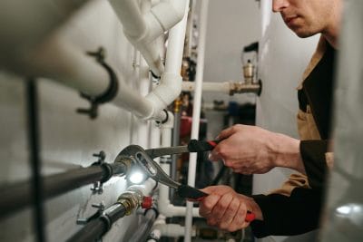 Technician inspecting commercial plumbing pipes in Fountain Valley