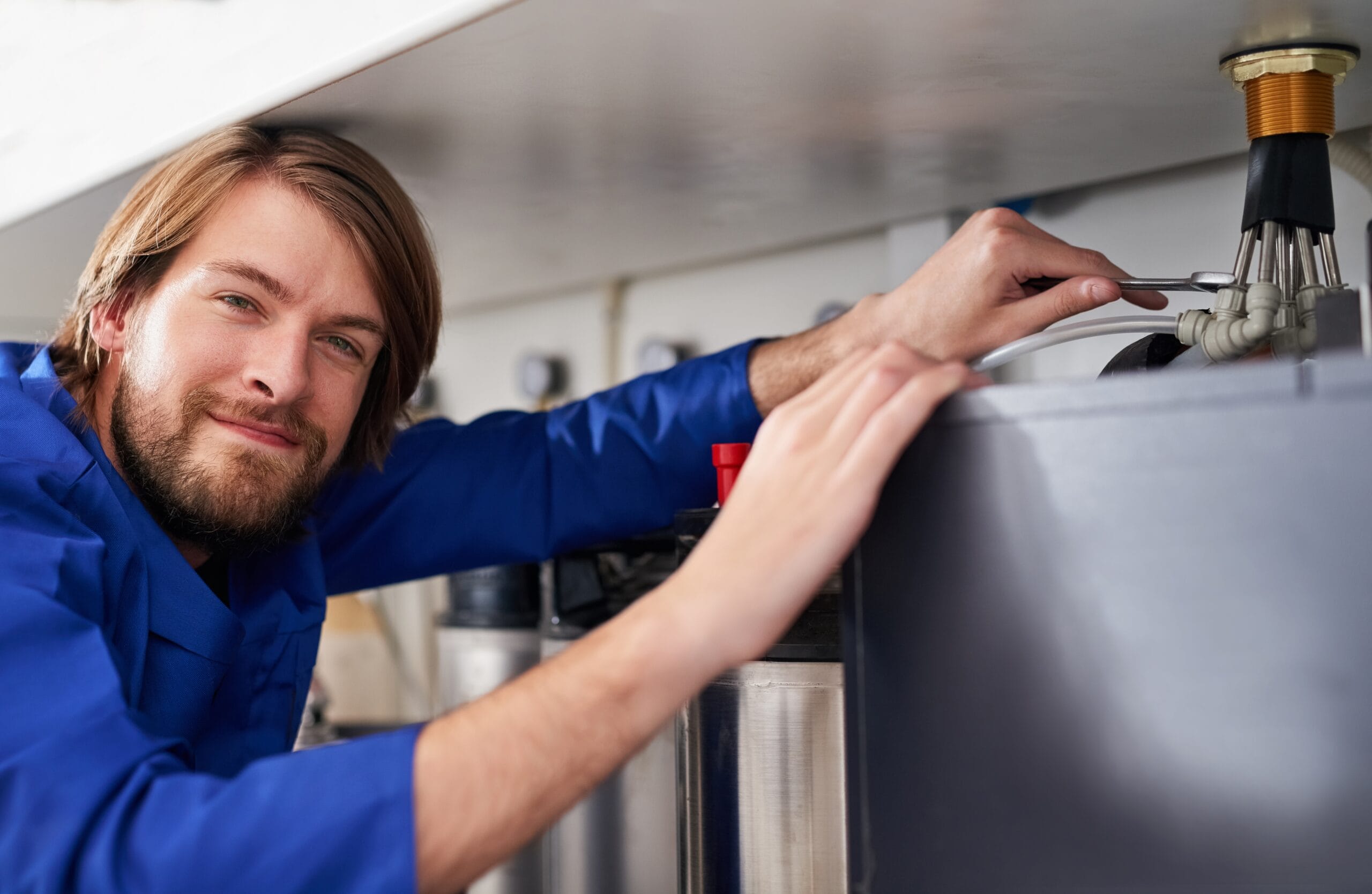 Technician servicing a residential water heater tank in Fountain Valley